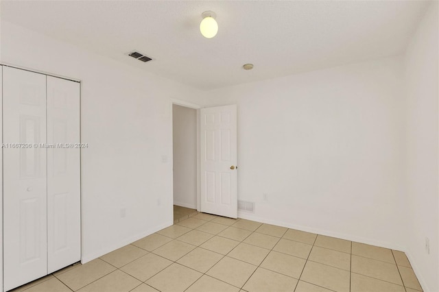 unfurnished room featuring a textured ceiling and light tile patterned floors