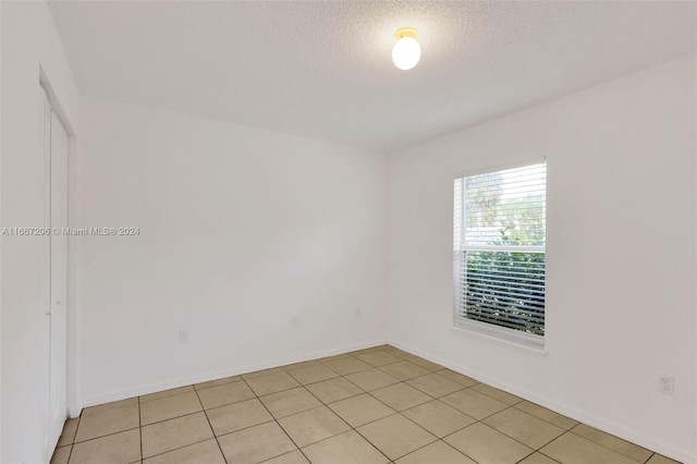 empty room featuring a textured ceiling and light tile patterned floors