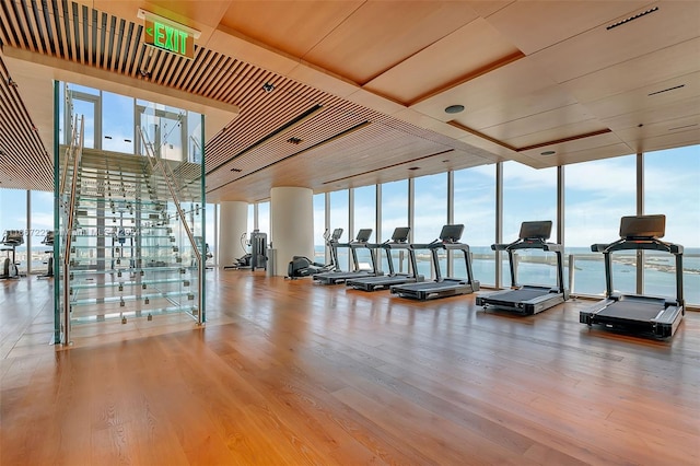 gym featuring a wall of windows, hardwood / wood-style floors, and a water view