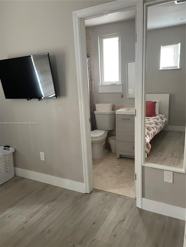 bathroom featuring curtained shower, wood-type flooring, toilet, and a wealth of natural light