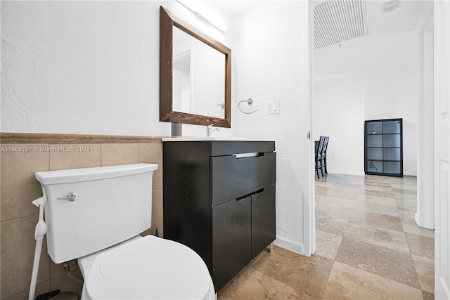 bathroom with tile walls, vanity, and toilet