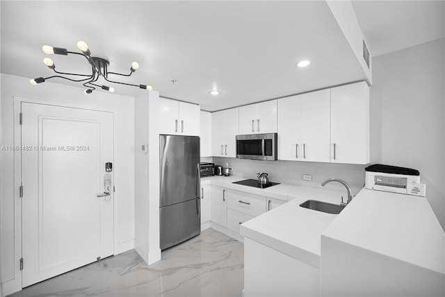 kitchen with a chandelier, sink, white cabinetry, stainless steel appliances, and backsplash