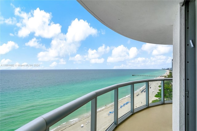 balcony featuring a view of the beach and a water view