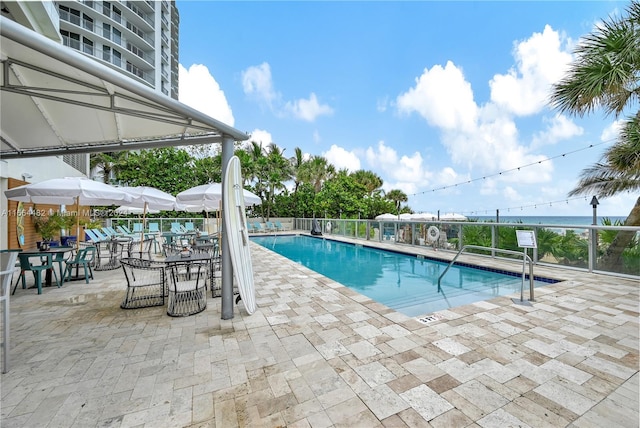 view of swimming pool featuring a water view and a patio area