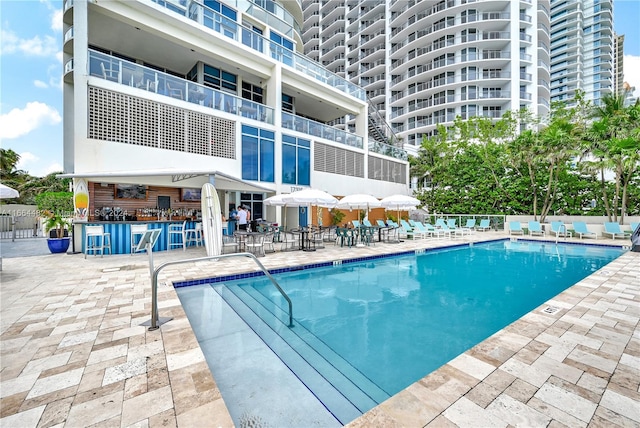 view of pool featuring exterior bar and a patio area