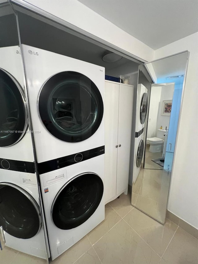 laundry area featuring stacked washer / dryer and light tile patterned floors