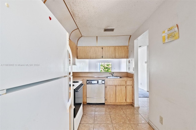 kitchen featuring white appliances, a textured ceiling, and light tile patterned floors