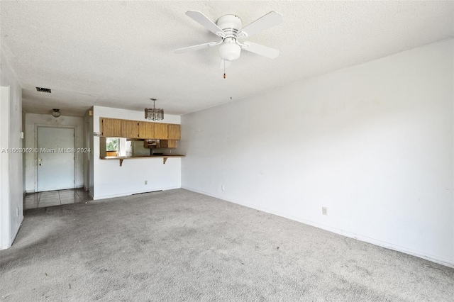 unfurnished living room featuring carpet, a textured ceiling, and ceiling fan