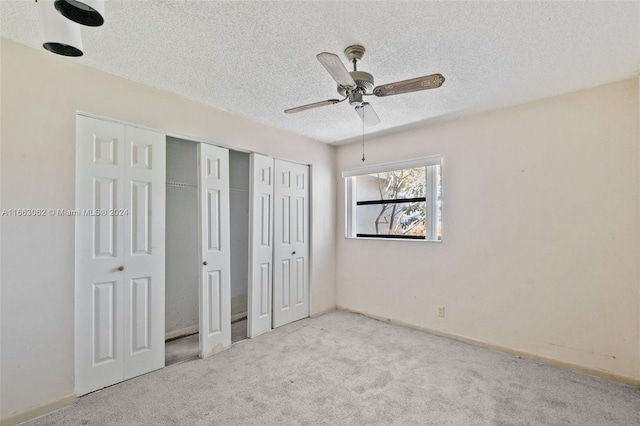 unfurnished bedroom featuring ceiling fan, light colored carpet, and a textured ceiling