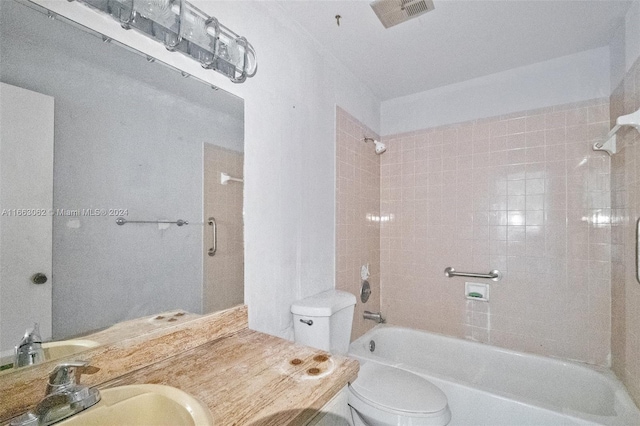 full bathroom featuring tiled shower / bath combo, vanity, and toilet