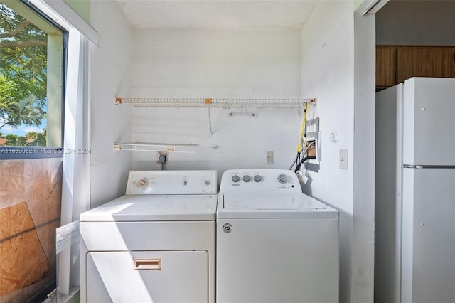 laundry area with washing machine and clothes dryer and a textured ceiling