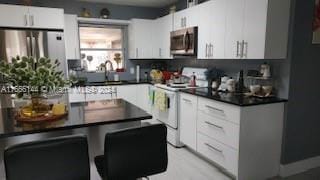 kitchen featuring white electric range, sink, tasteful backsplash, and white cabinetry