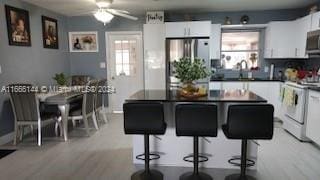 kitchen with a kitchen breakfast bar, stainless steel fridge, and white cabinetry