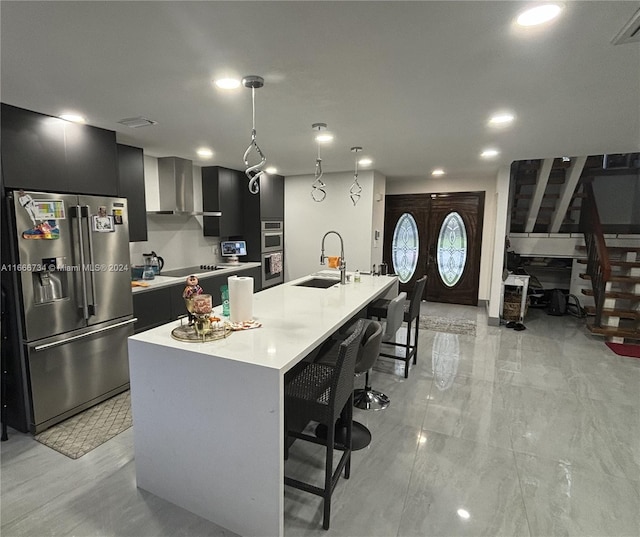 kitchen featuring a kitchen island with sink, sink, pendant lighting, appliances with stainless steel finishes, and a kitchen breakfast bar