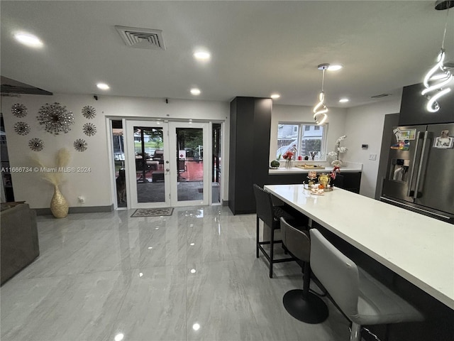 kitchen featuring pendant lighting, french doors, a breakfast bar, and stainless steel refrigerator with ice dispenser