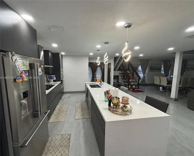 kitchen featuring pendant lighting, stainless steel fridge with ice dispenser, sink, and a large island