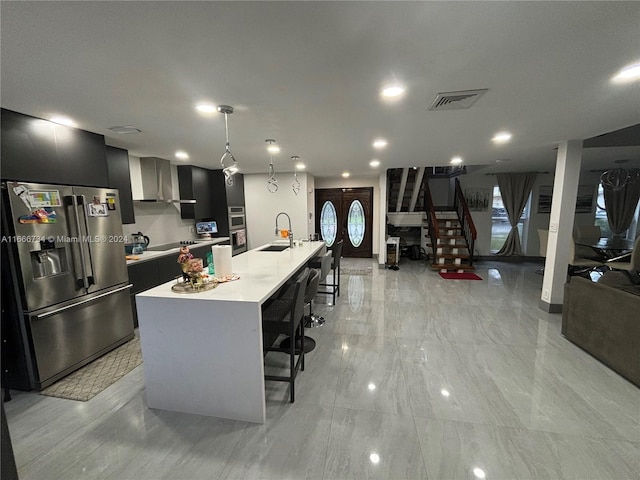 kitchen with pendant lighting, sink, a large island with sink, appliances with stainless steel finishes, and a kitchen bar