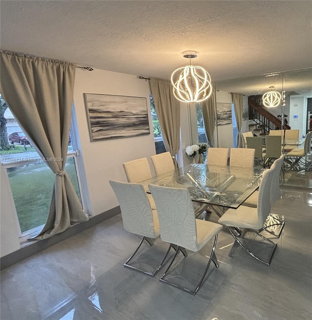 dining area featuring a notable chandelier, a wealth of natural light, and a textured ceiling