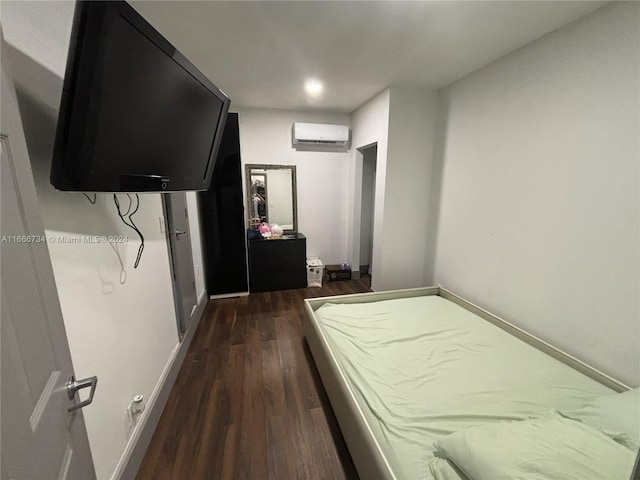 bedroom with a wall unit AC and dark hardwood / wood-style flooring