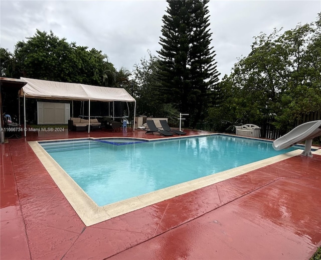 view of swimming pool featuring a water slide and a patio