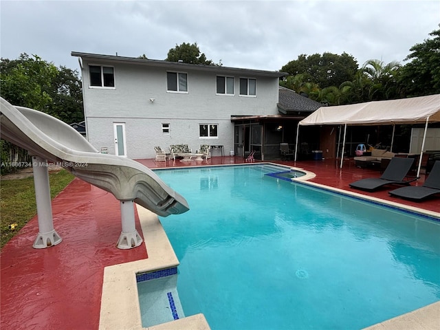 view of pool featuring a water slide and a patio