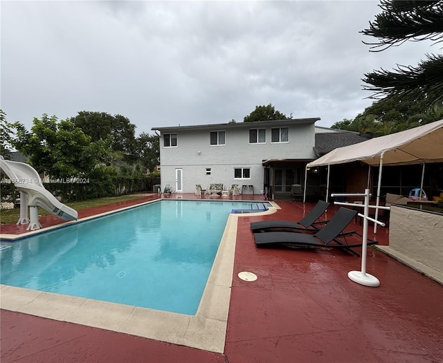 view of swimming pool featuring a water slide and a patio area