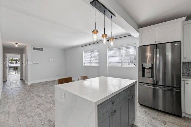 kitchen featuring stainless steel fridge with ice dispenser, hanging light fixtures, gray cabinets, a kitchen island, and white cabinets