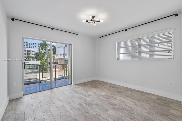 unfurnished room with light hardwood / wood-style flooring and a notable chandelier