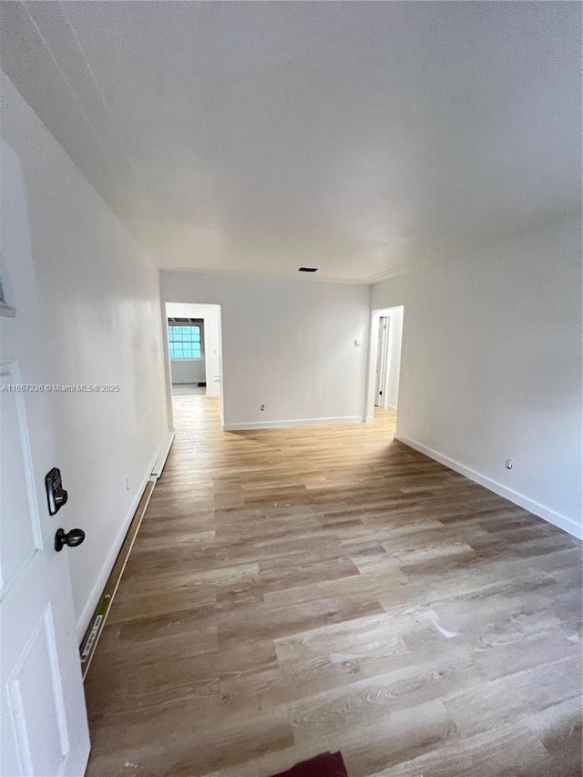 spare room featuring light wood finished floors and baseboards