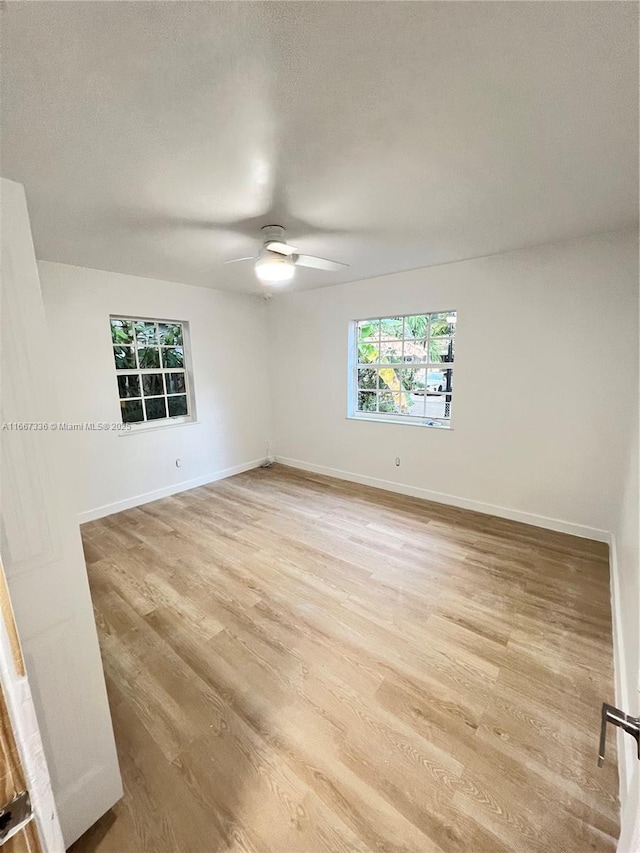empty room with light wood-type flooring, baseboards, a textured ceiling, and a ceiling fan