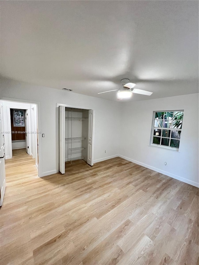 unfurnished bedroom featuring light wood finished floors, visible vents, baseboards, and a closet