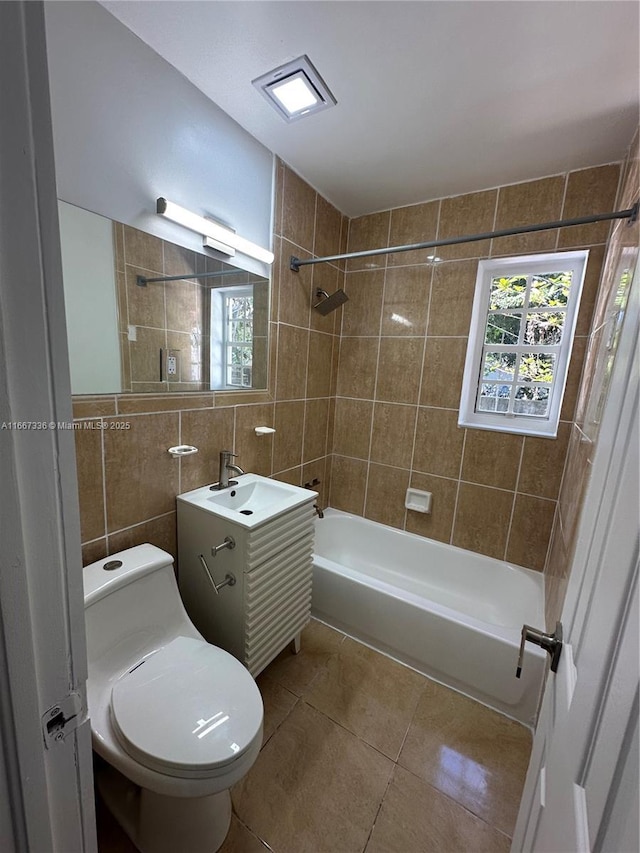 full bath with tile patterned floors, toilet, tile walls, shower / bath combination, and vanity