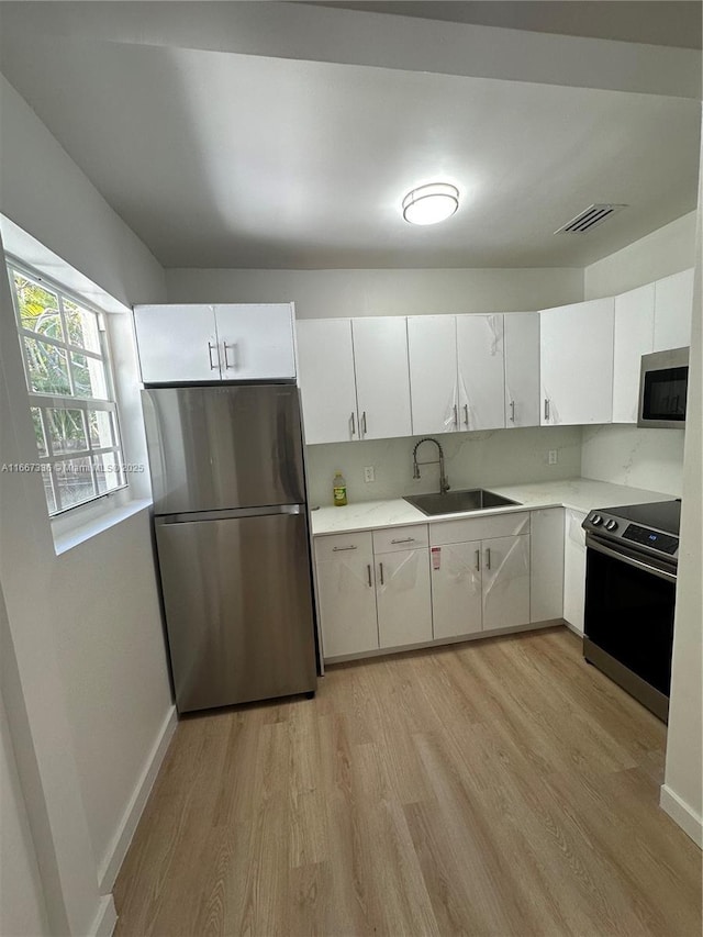 kitchen featuring visible vents, light countertops, appliances with stainless steel finishes, light wood-style floors, and a sink