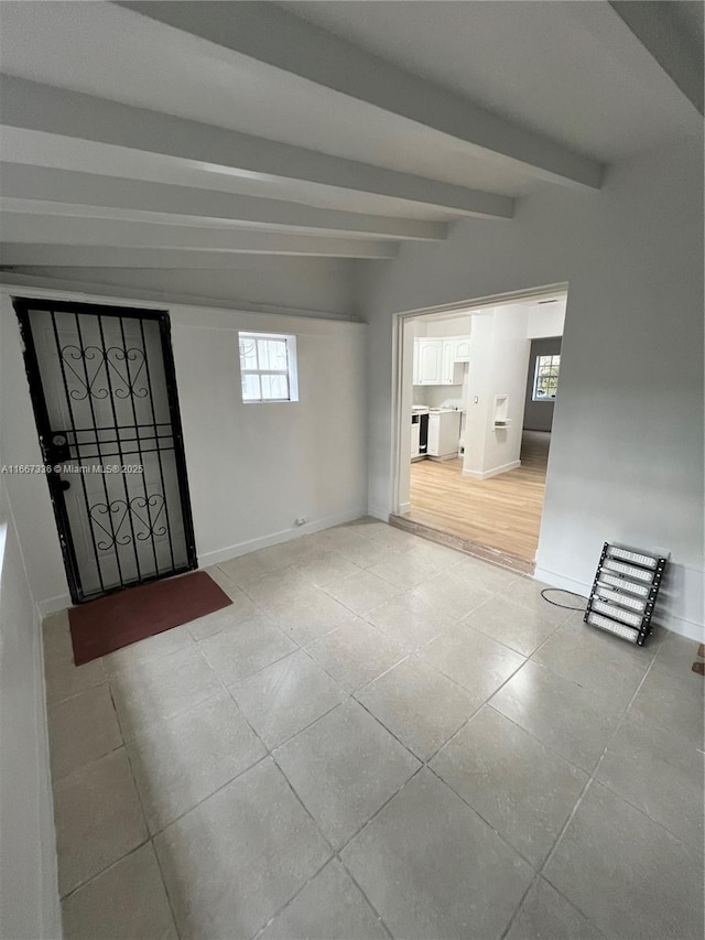 empty room featuring tile patterned floors, baseboards, and beam ceiling