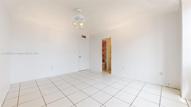 empty room featuring a textured ceiling and light tile patterned floors