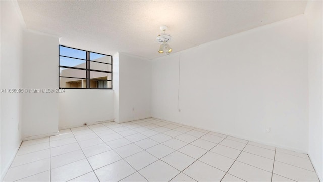 empty room featuring a textured ceiling and light tile patterned floors