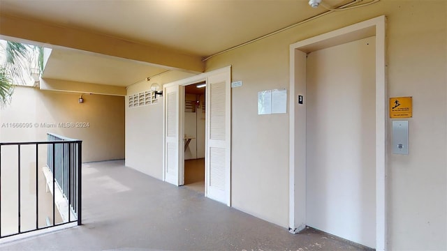 hallway featuring elevator and concrete flooring