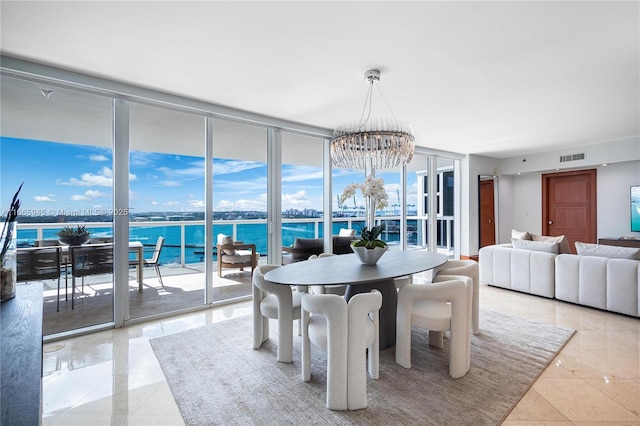 dining room featuring floor to ceiling windows, a water view, and a chandelier