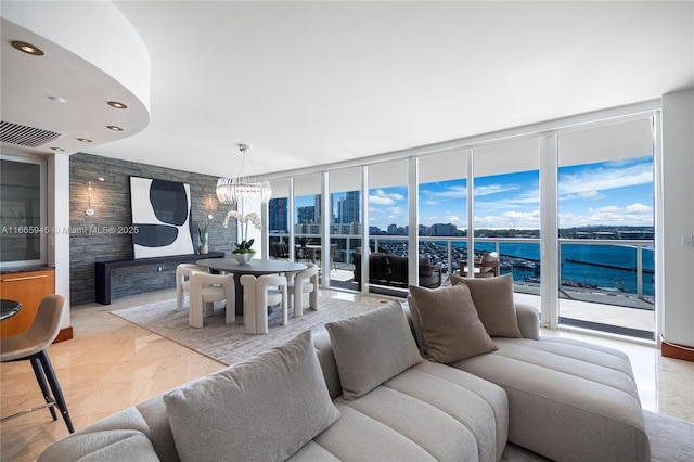 living room featuring expansive windows, a water view, and a notable chandelier