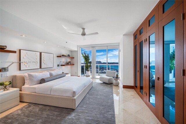 bedroom featuring a water view, ceiling fan, expansive windows, and access to exterior