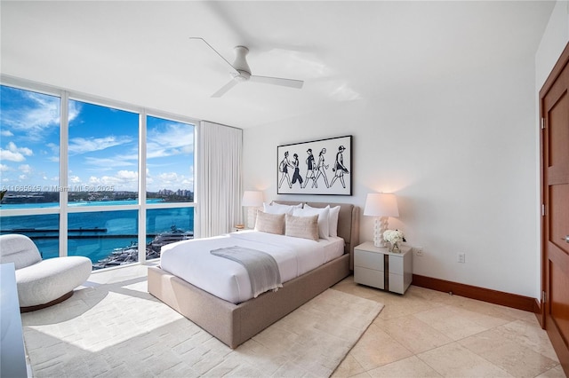 bedroom with light tile patterned floors, a wall of windows, ceiling fan, and a water view