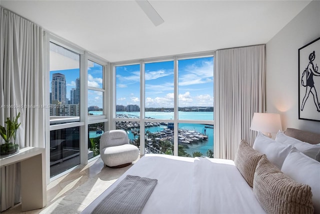 bedroom with a water view, a wall of windows, and ceiling fan