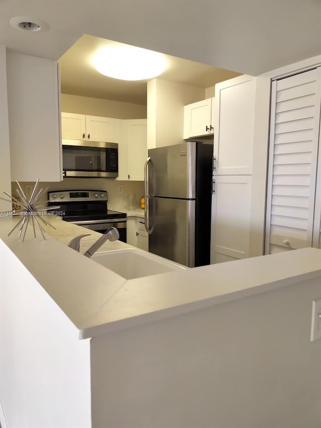 kitchen featuring sink, white cabinetry, kitchen peninsula, and appliances with stainless steel finishes