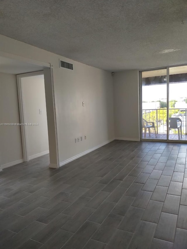 empty room with dark hardwood / wood-style flooring and a textured ceiling