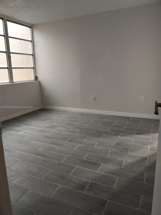 empty room with a textured ceiling and dark hardwood / wood-style floors