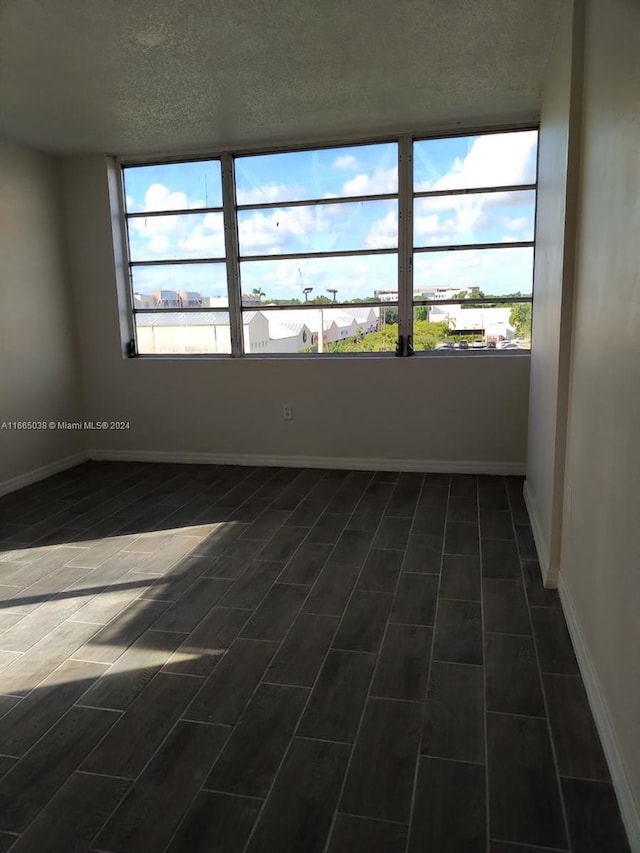 spare room with dark hardwood / wood-style flooring and a textured ceiling