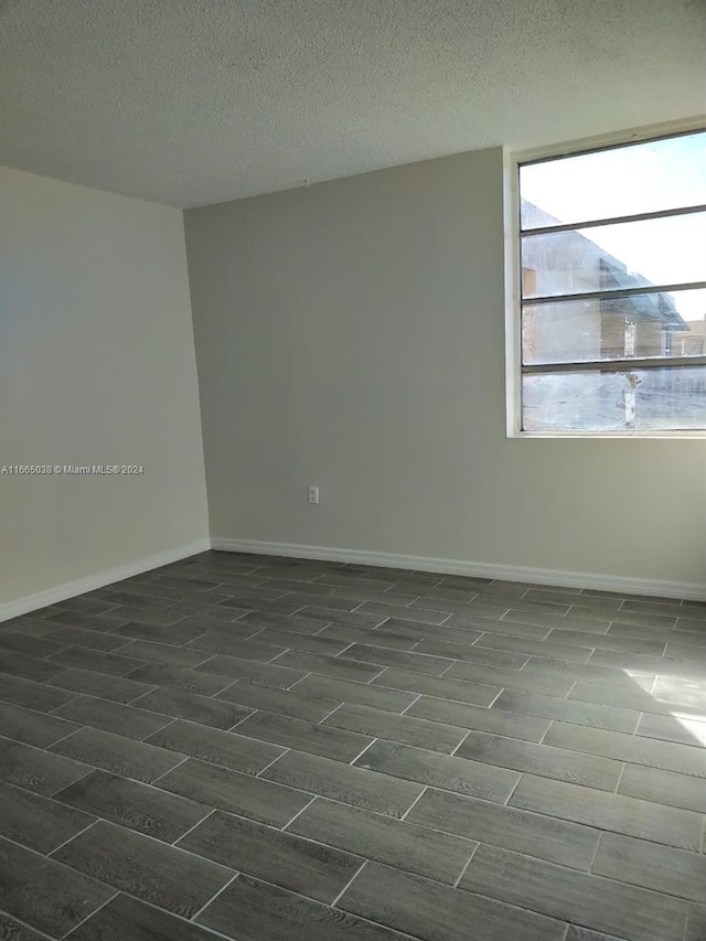 unfurnished room with a textured ceiling and dark hardwood / wood-style floors