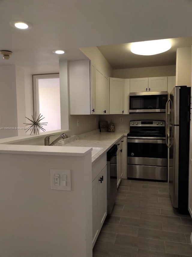 kitchen with white cabinetry, sink, kitchen peninsula, and stainless steel appliances