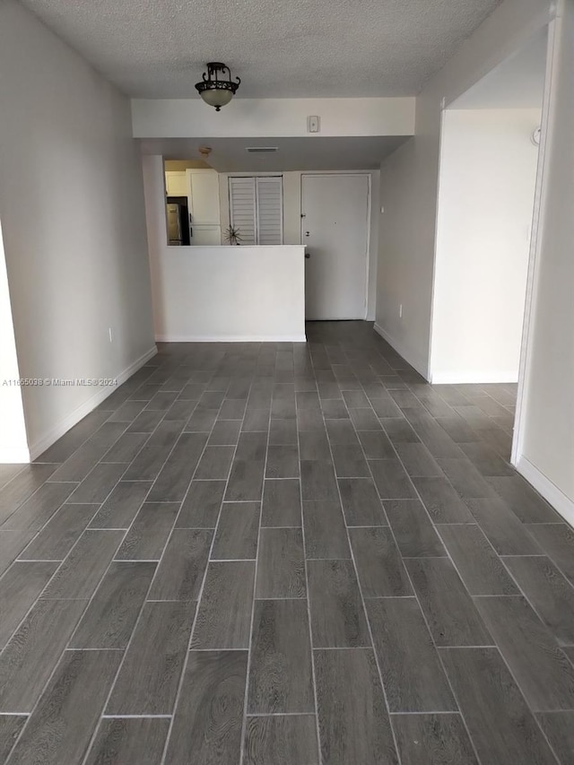 unfurnished living room with dark hardwood / wood-style flooring and a textured ceiling