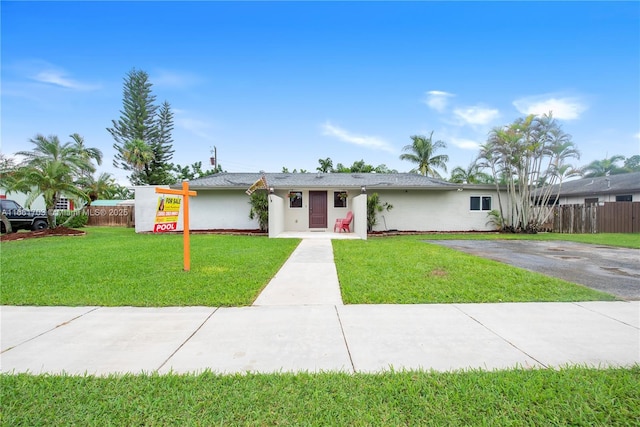 view of front of home featuring stucco siding, fence, and a front yard